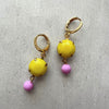 Pair of earrings with yellow and pink beads on a gray background