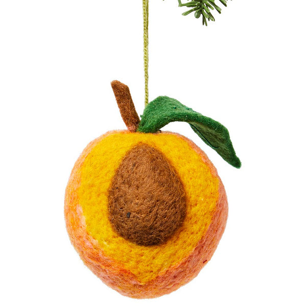 Felted peach ornament hanging from a branch on a white background
