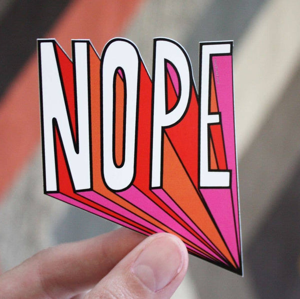 Colorful 'NOPE' sticker held by a hand with a blurred background