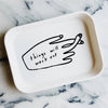 White tray with a black hand-drawn illustration and text 'things will work out' on a marble surface