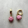 Gold and pink earrings on a light gray background