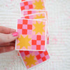Hand holding colorful checkered cards with star patterns on a textured surface.