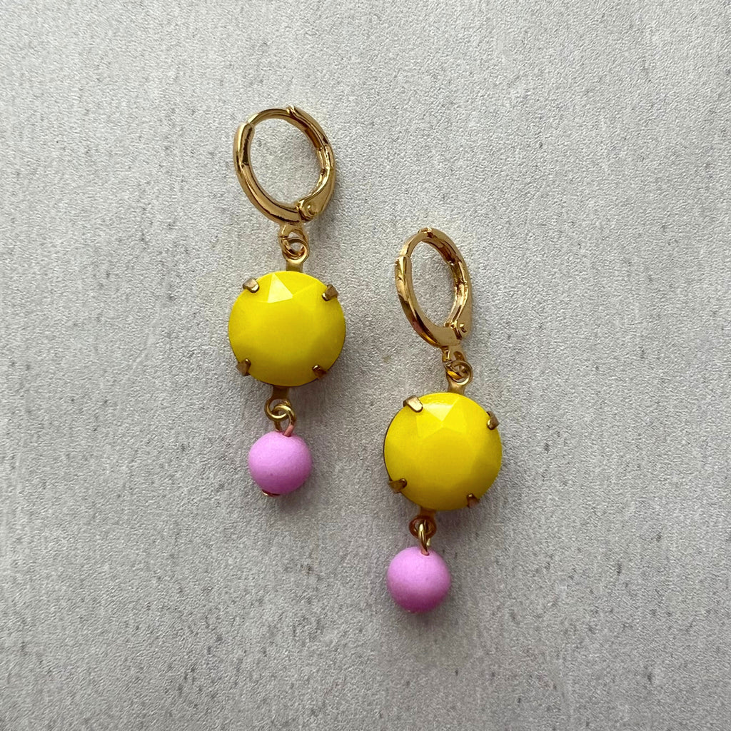 Pair of earrings with yellow and pink beads on a gray background