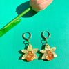 Flower-shaped earrings on a green background