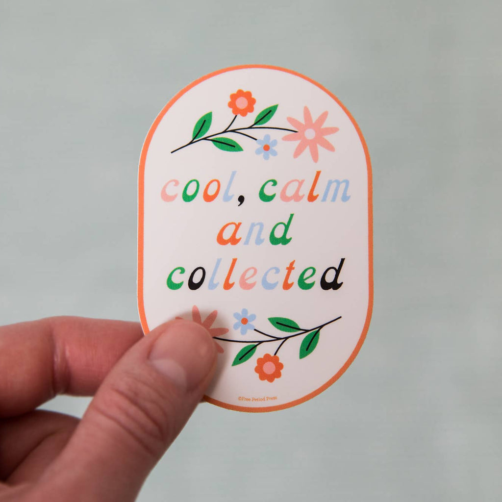 Hand holding a sticker with 'cool, calm and collected' text and floral designs on a gray background