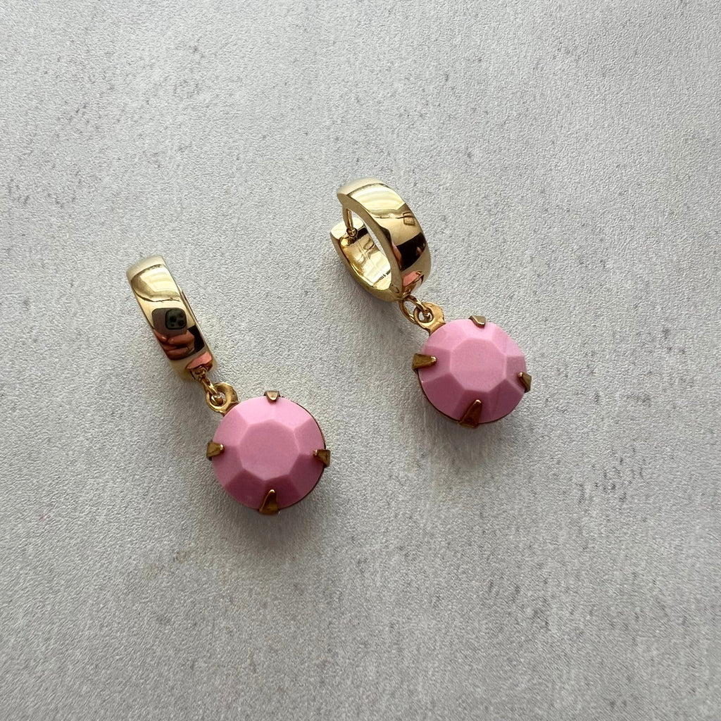 Gold earrings with pink gemstones on a light gray background