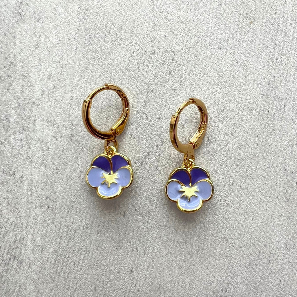 Gold hoop earrings with blue and white flower charms on a light gray background