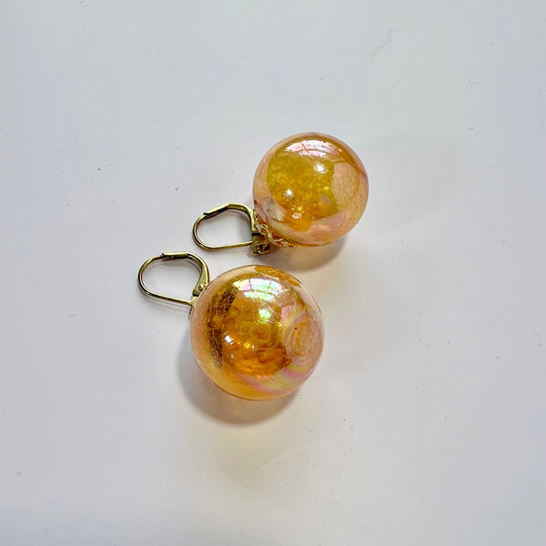 Pair of gold and orange round earrings on a white background