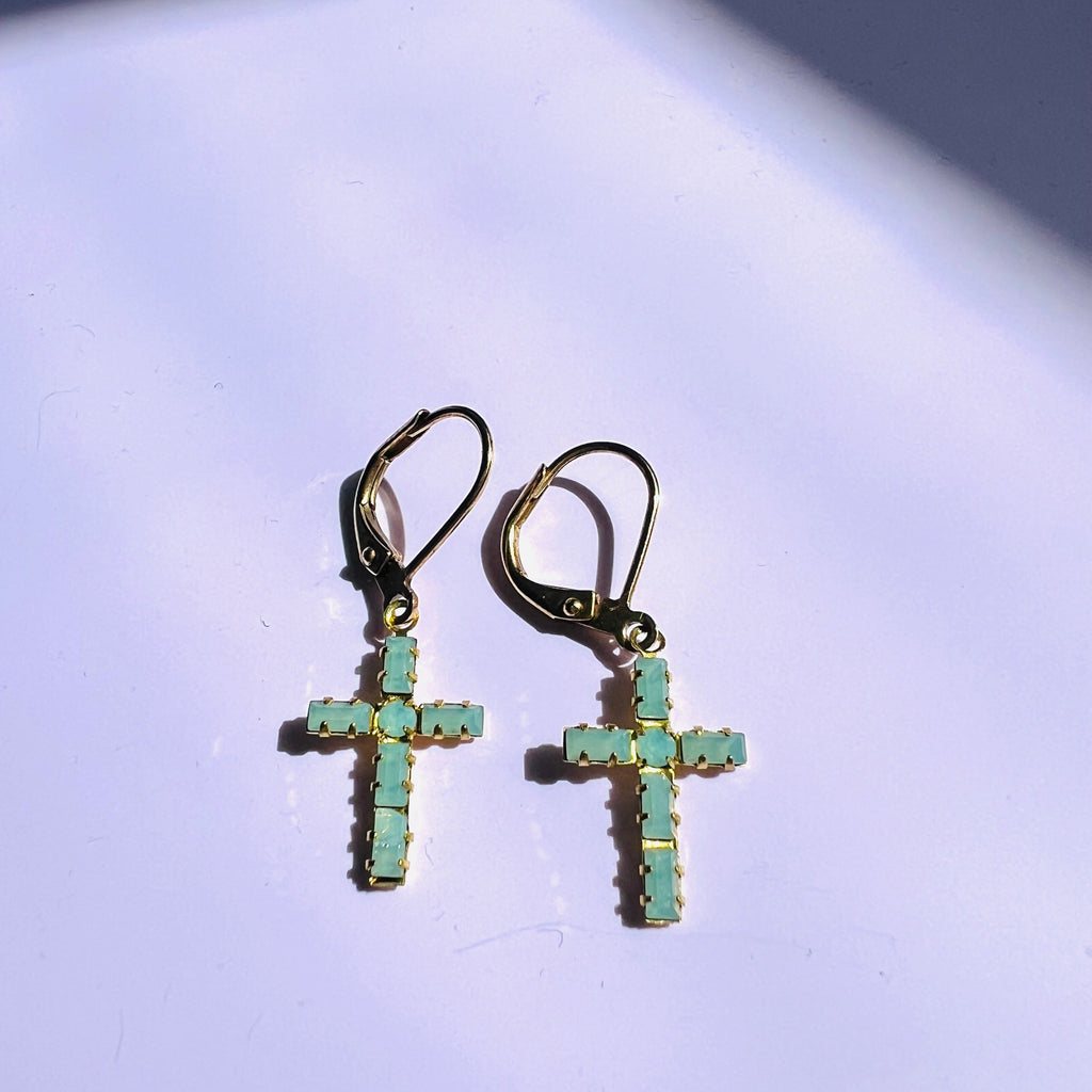 Cross-shaped earrings with turquoise stones on a light background