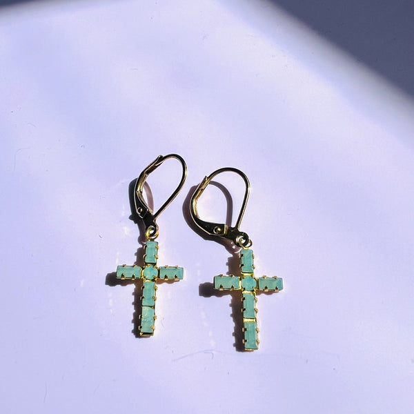 Cross-shaped earrings with turquoise stones on a light background