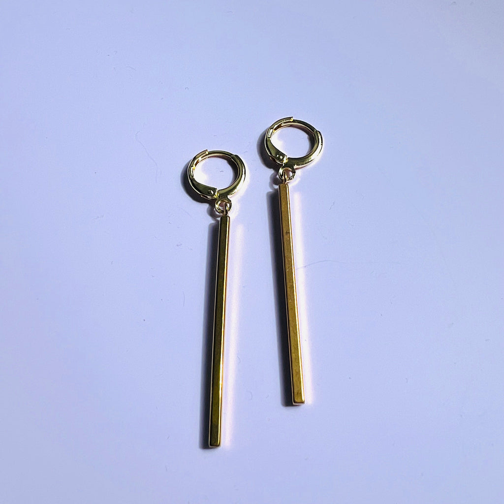 Gold earrings on a light purple background
