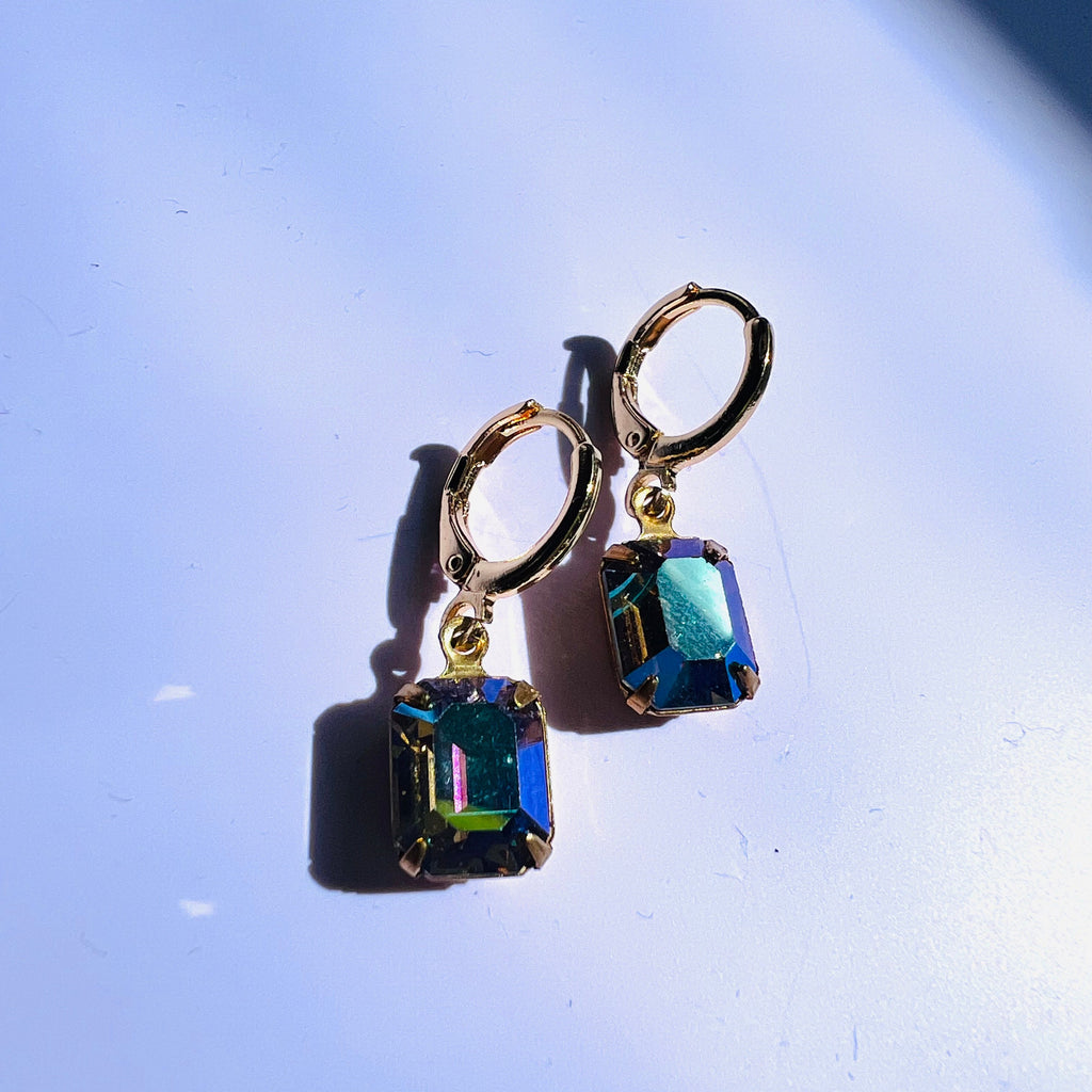 Gold earrings with blue gemstones on a light blue background
