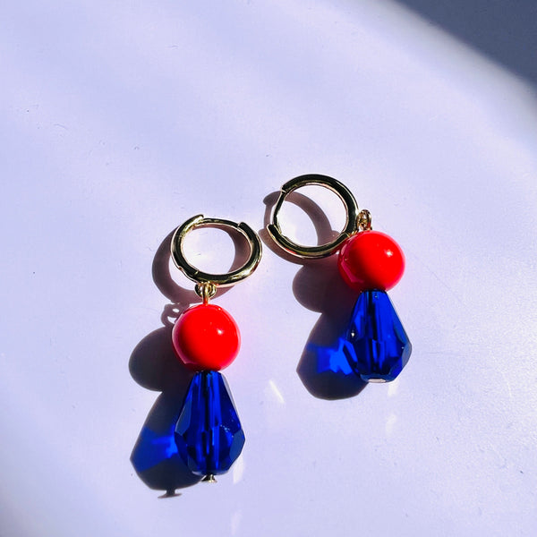 Pair of earrings with blue and red beads on a white background