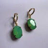 Green earrings with gold hooks on a white background