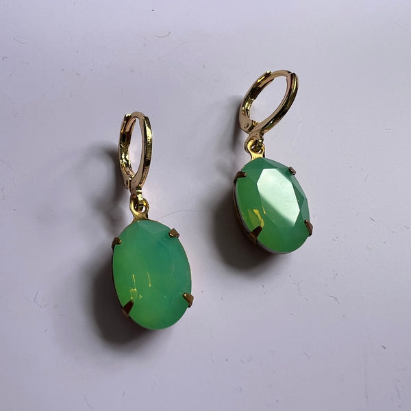 Green earrings with gold hooks on a white background