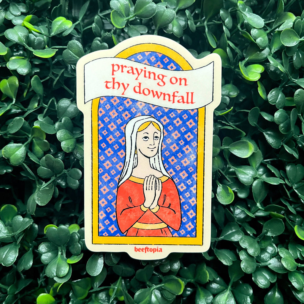 Card with a praying figure and text 'praying on thy downfall' on a green leafy background
