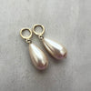 Pearl earrings with gold hooks on a gray surface