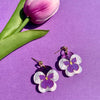 Flower-shaped earrings on a purple background with a pink tulip.