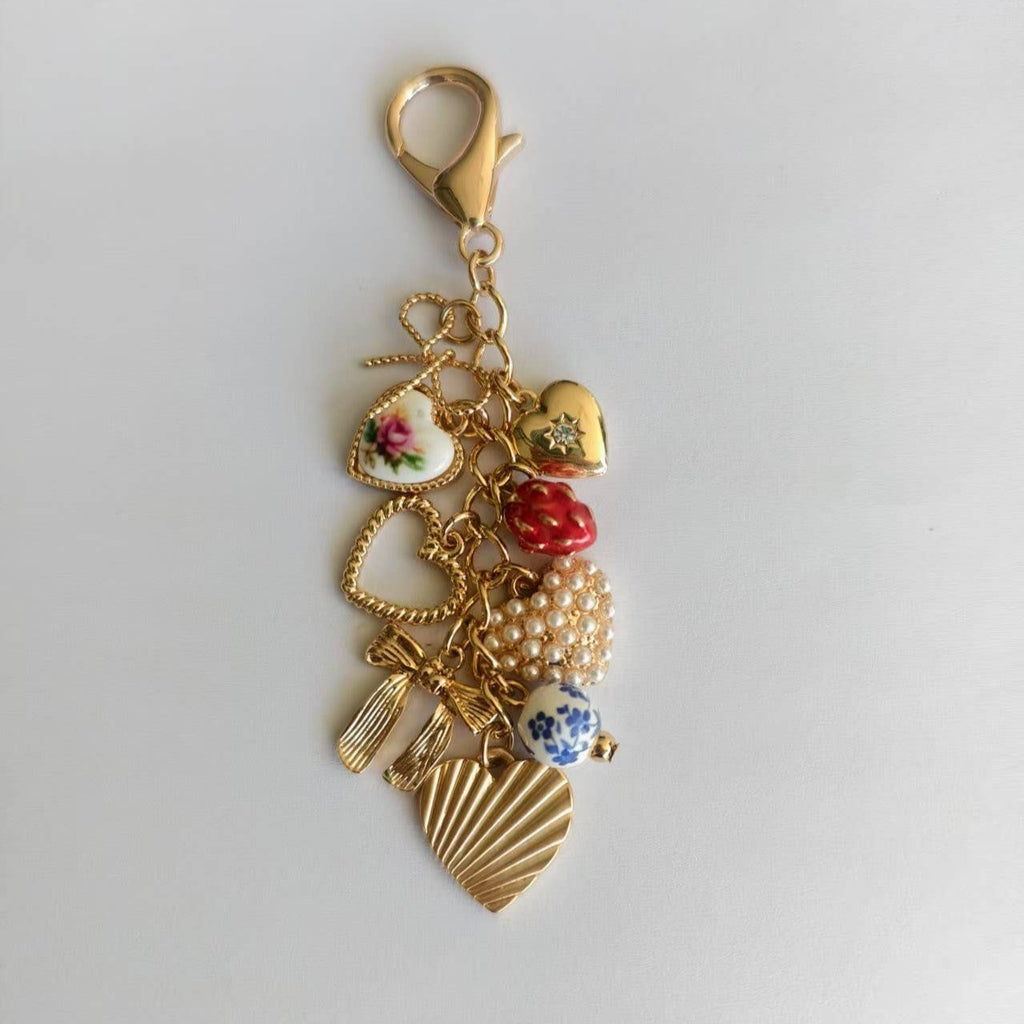 Gold keychain with various charms on a light gray background