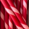 A close-up of red and white striped taper candles arranged tightly together, resembling candy canes.